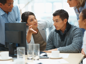 Three people around a computer